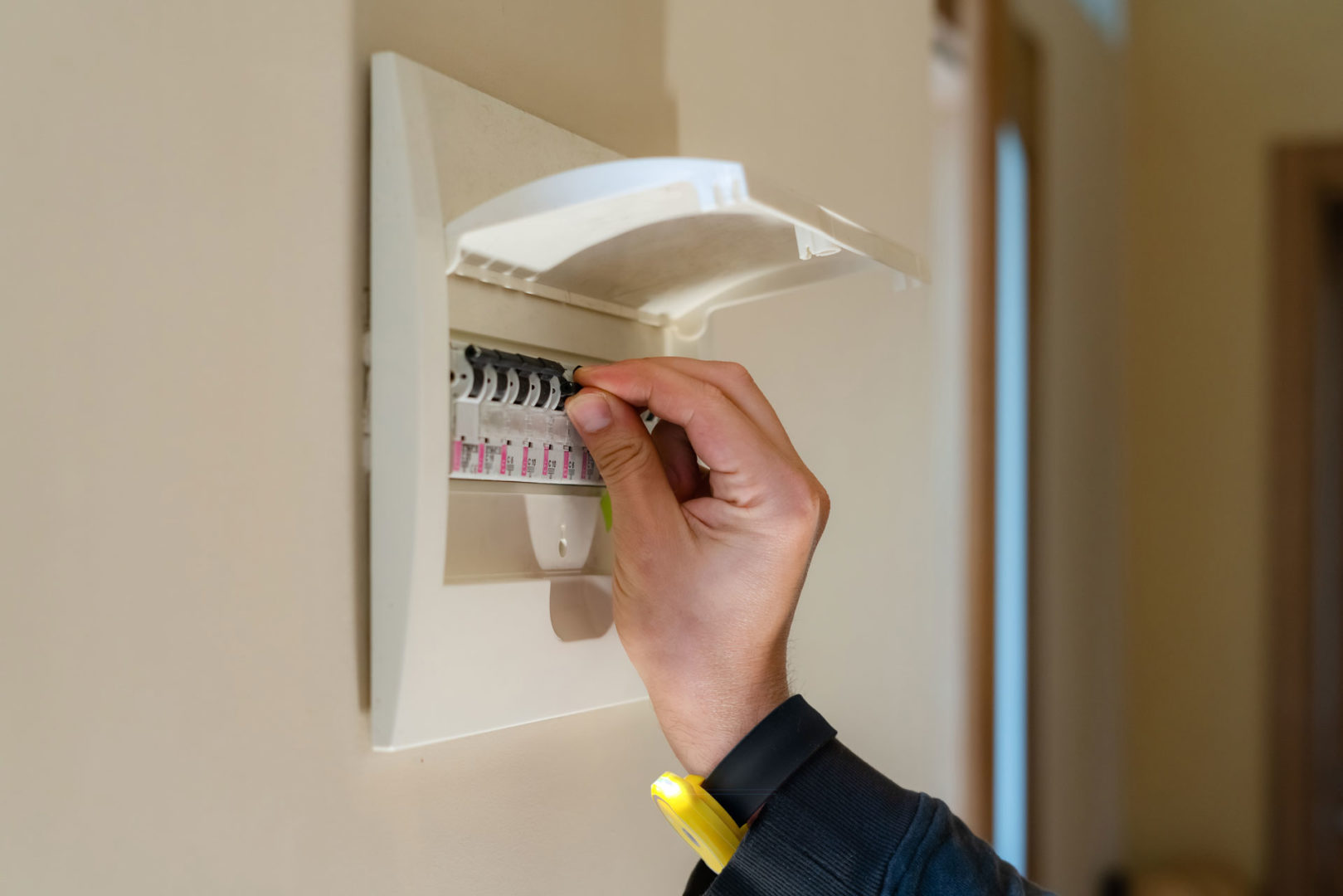 A man wearing a Twistii checking a fuse board.