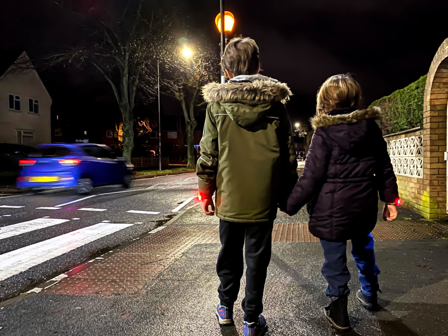 Two children walking alongside a busy road.